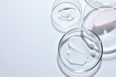 Photo of Different cosmetic products in Petri dishes on white background, flat lay. Space for text