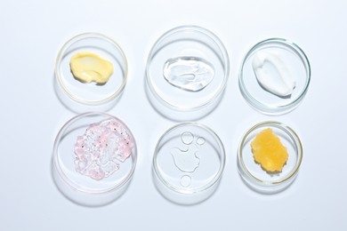 Photo of Different cosmetic products in Petri dishes on white background, flat lay