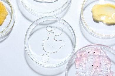 Photo of Different cosmetic products in Petri dishes on white background, flat lay