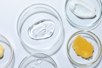 Photo of Different cosmetic products in Petri dishes on white background, flat lay