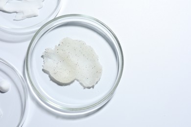 Photo of Different cosmetic products in Petri dishes on white background, flat lay. Space for text