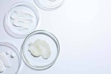 Photo of Different cosmetic products in Petri dishes on white background, flat lay. Space for text
