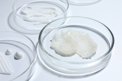 Photo of Different cosmetic products in Petri dishes on white background, closeup