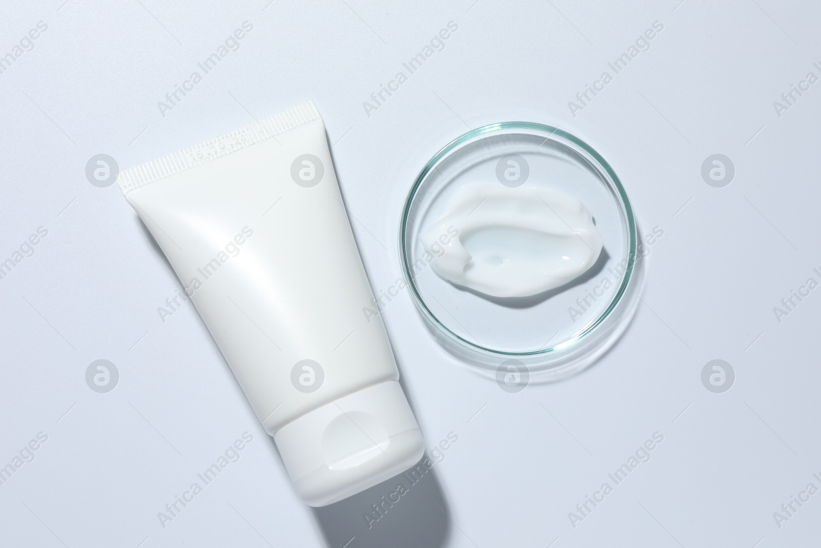 Cosmetic product in Petri dish and tube on white background, top view Photo of Cosmetic product in Petri dish and tube on white background, top view