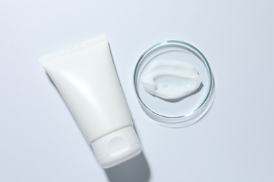 Photo of Cosmetic product in Petri dish and tube on white background, top view