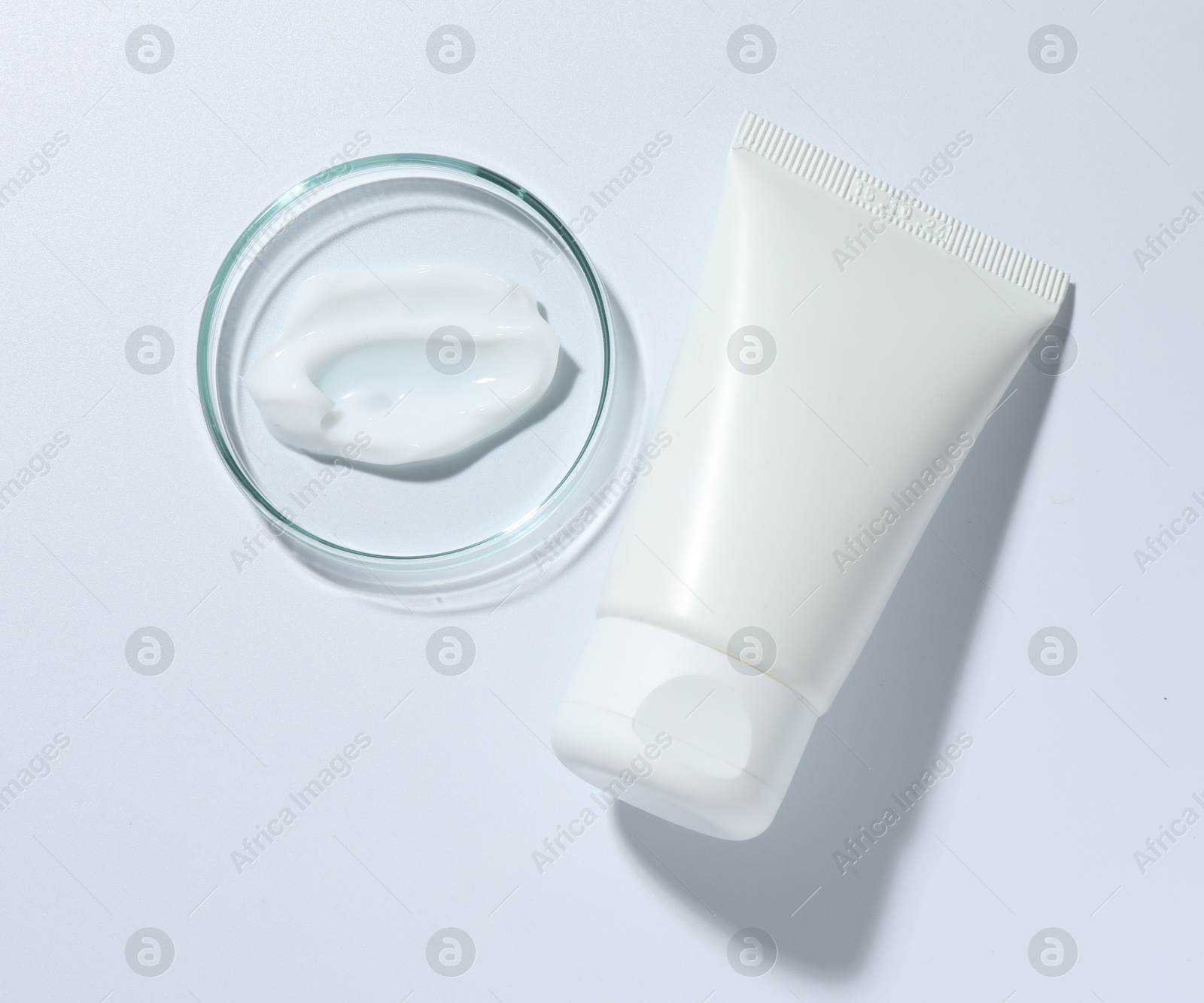Cosmetic product in Petri dish and tube on white background, top view Photo of Cosmetic product in Petri dish and tube on white background, top view