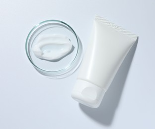 Photo of Cosmetic product in Petri dish and tube on white background, top view