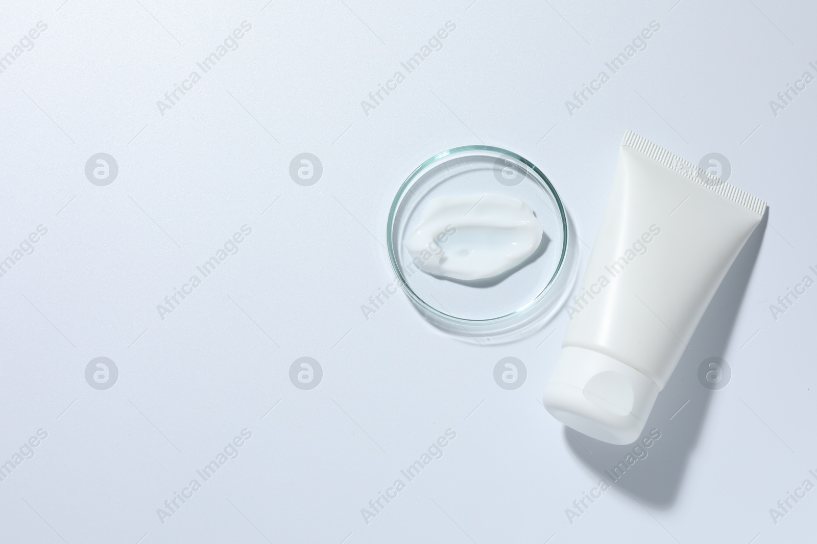 Cosmetic product in Petri dish and tube on white background, top view. Space for text Photo of Cosmetic product in Petri dish and tube on white background, top view. Space for text