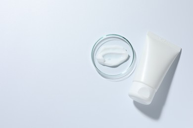 Photo of Cosmetic product in Petri dish and tube on white background, top view. Space for text