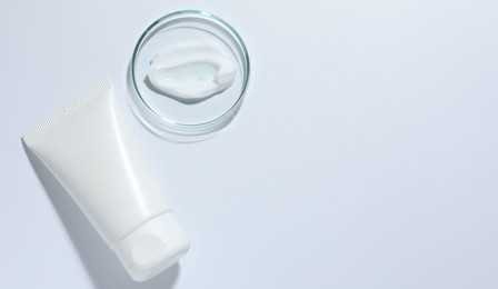 Photo of Cosmetic product in Petri dish and tube on white background, top view. Space for text