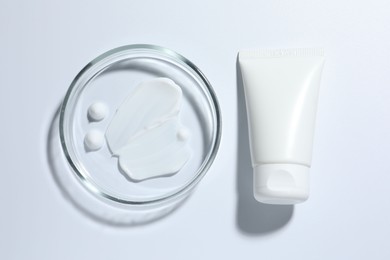 Photo of Cosmetic product in Petri dish and tube on white background, top view