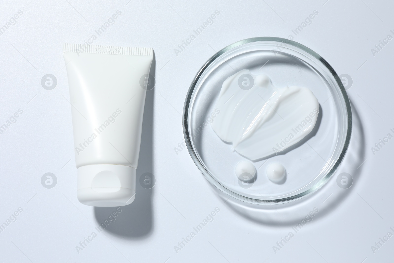 Cosmetic product in Petri dish and tube on white background, top view Photo of Cosmetic product in Petri dish and tube on white background, top view