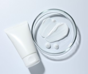 Photo of Cosmetic product in Petri dish and tube on white background, top view