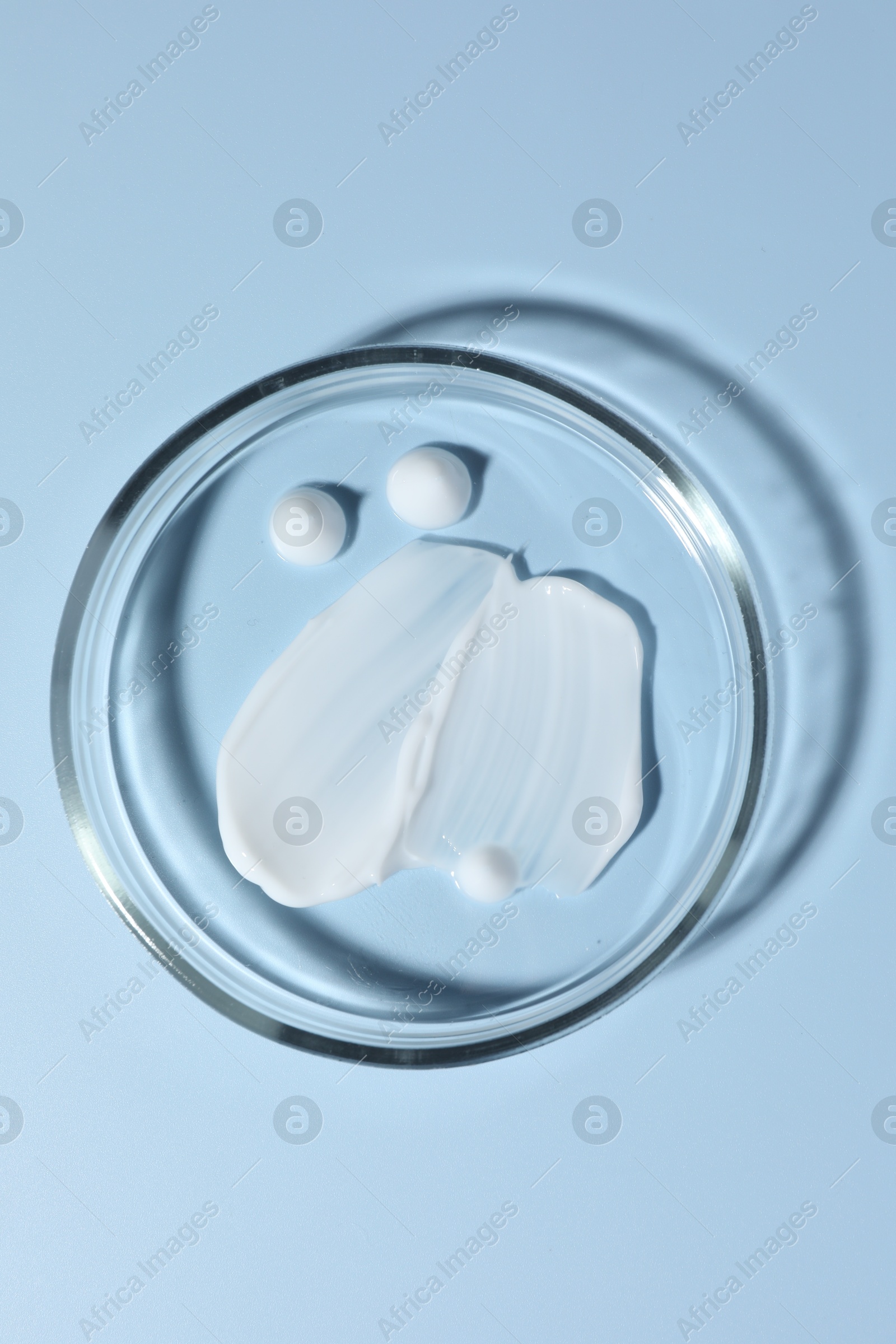 Cosmetic product in Petri dish on light blue background, top view Photo of Cosmetic product in Petri dish on light blue background, top view