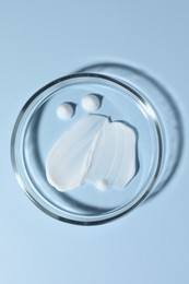 Photo of Cosmetic product in Petri dish on light blue background, top view