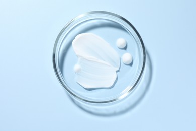 Photo of Cosmetic product in Petri dish on light blue background, top view