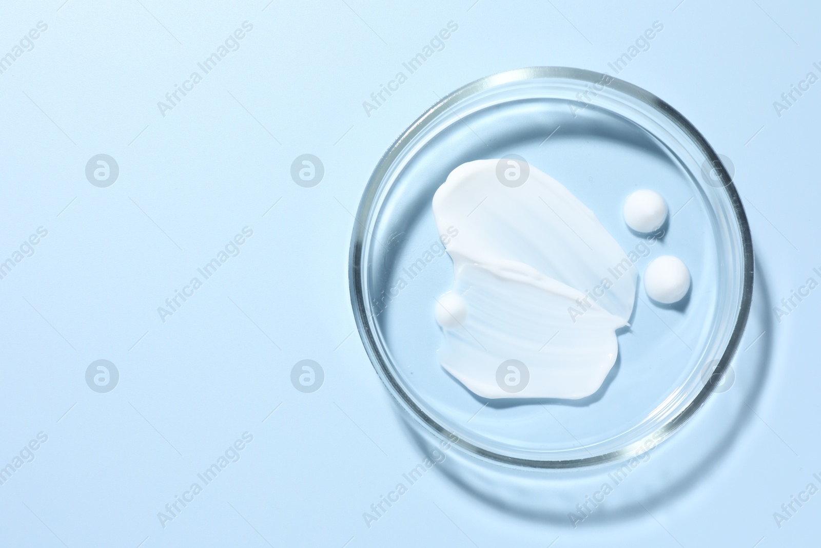 Cosmetic product in Petri dish on light blue background, top view. Space for text Photo of Cosmetic product in Petri dish on light blue background, top view. Space for text