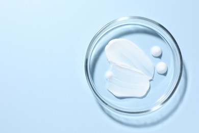 Photo of Cosmetic product in Petri dish on light blue background, top view. Space for text