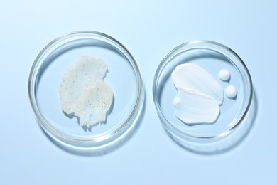 Photo of Different cosmetic products in Petri dishes on light blue background, flat lay