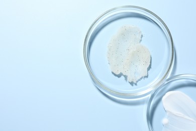 Photo of Different cosmetic products in Petri dishes on light blue background, flat lay. Space for text