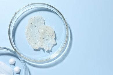 Photo of Different cosmetic products in Petri dishes on light blue background, flat lay. Space for text