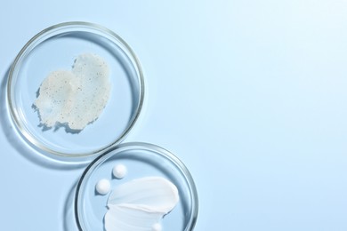 Photo of Different cosmetic products in Petri dishes on light blue background, flat lay. Space for text