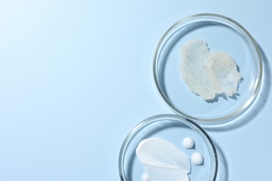 Photo of Different cosmetic products in Petri dishes on light blue background, flat lay. Space for text