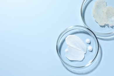 Photo of Different cosmetic products in Petri dishes on light blue background, flat lay. Space for text