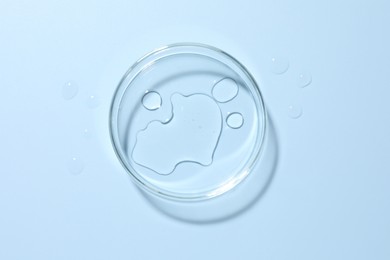 Photo of Cosmetic product in Petri dish on light blue background, top view