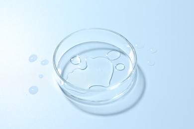 Photo of Cosmetic product in Petri dish on light blue background, closeup