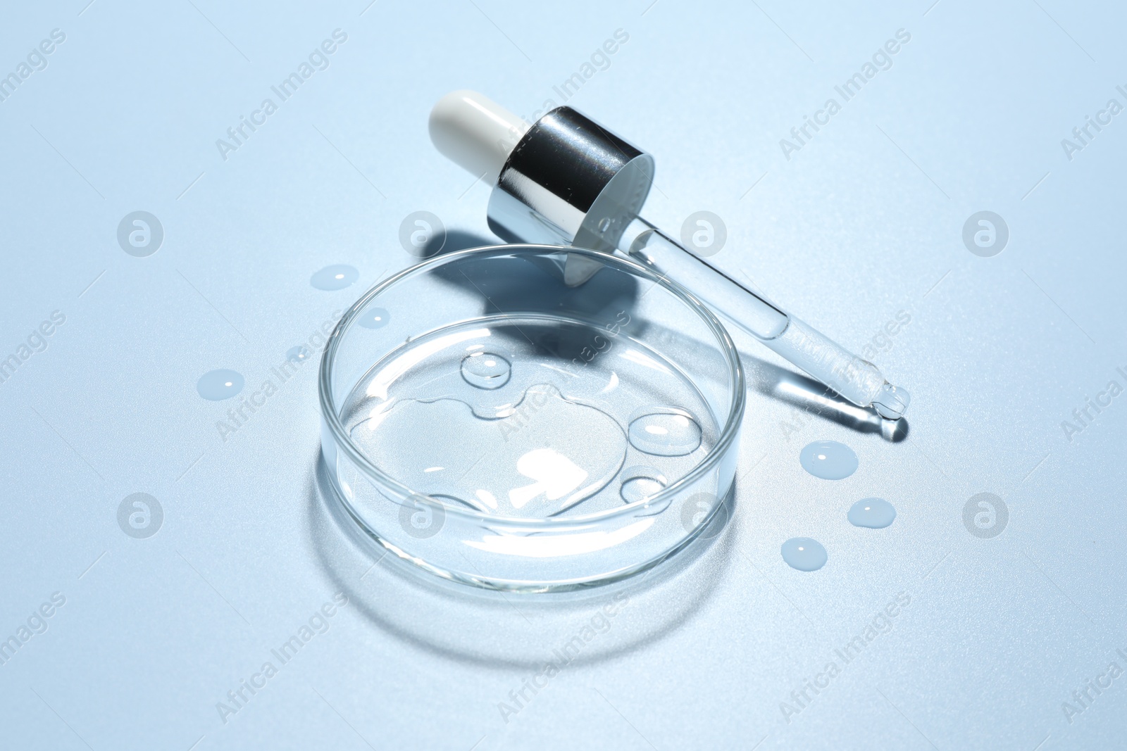 Cosmetic product in Petri dish and dropper on light blue background, closeup Photo of Cosmetic product in Petri dish and dropper on light blue background, closeup