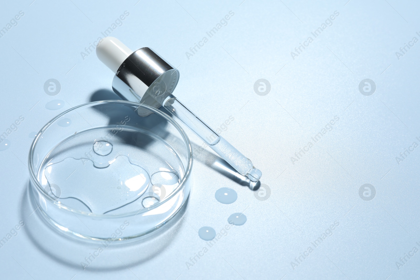 Cosmetic product in Petri dish and dropper on light blue background, closeup. Space for text Photo of Cosmetic product in Petri dish and dropper on light blue background, closeup. Space for text