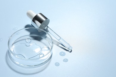 Photo of Cosmetic product in Petri dish and dropper on light blue background, closeup. Space for text