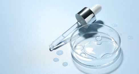 Photo of Cosmetic product in Petri dish and dropper on light blue background, closeup. Space for text