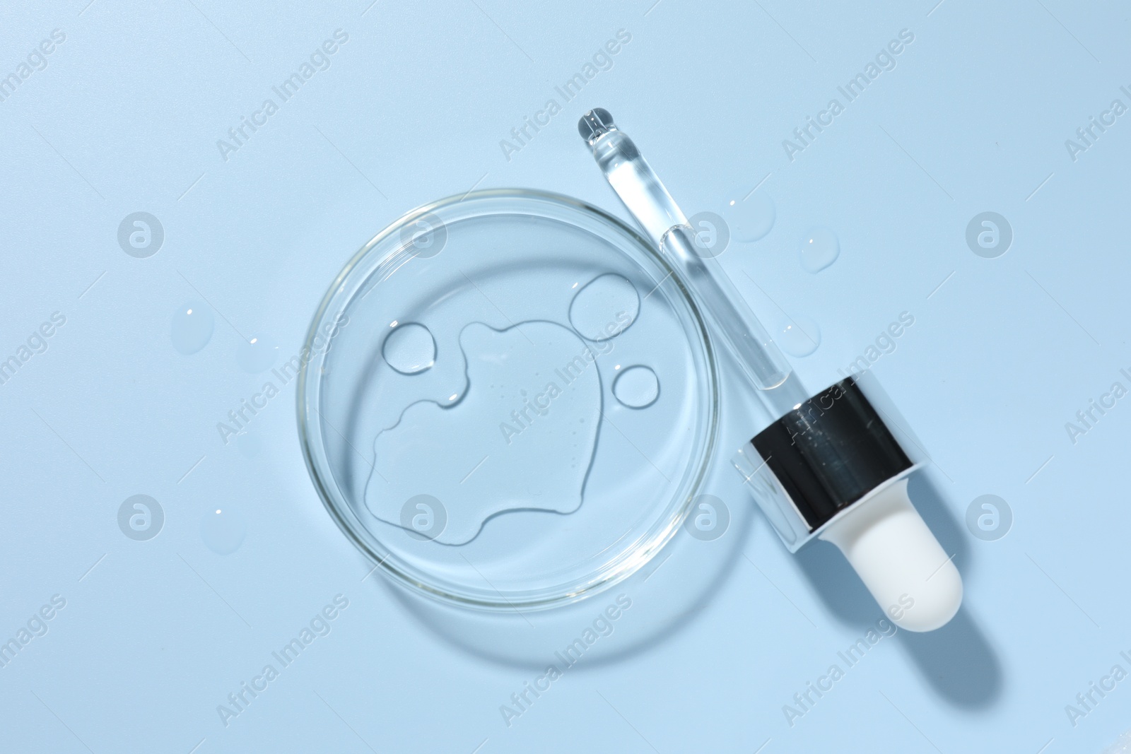 Cosmetic product in Petri dish and dropper on light blue background, top view Photo of Cosmetic product in Petri dish and dropper on light blue background, top view