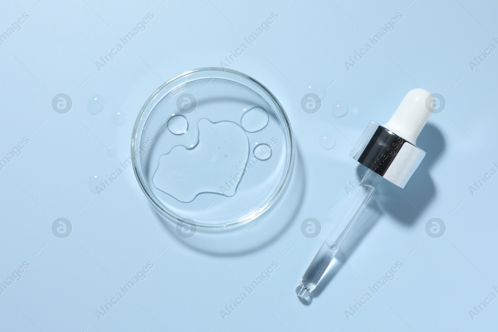 Cosmetic product in Petri dish and dropper on light blue background, top view Photo of Cosmetic product in Petri dish and dropper on light blue background, top view