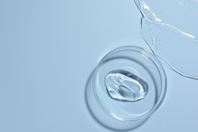 Photo of Cosmetic product in Petri dish on light blue background, top view. Space for text
