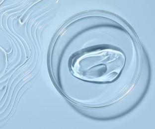 Photo of Cosmetic product in Petri dish on light blue background, top view