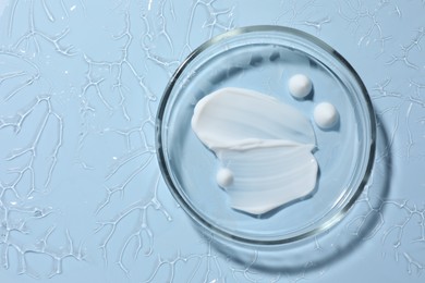 Photo of Cosmetic product in Petri dish on light blue background, top view