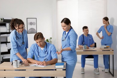 Photo of Medical students in uniforms studying together at university