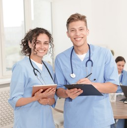 Photo of Medical students in uniforms studying together indoors, selective focus