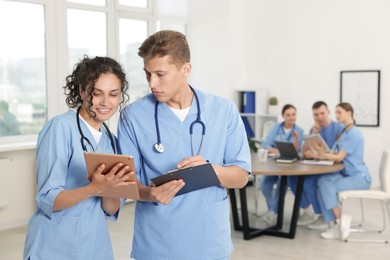 Photo of Medical students in uniforms studying together indoors, selective focus