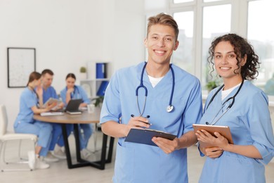 Photo of Medical students in uniforms studying together indoors, selective focus