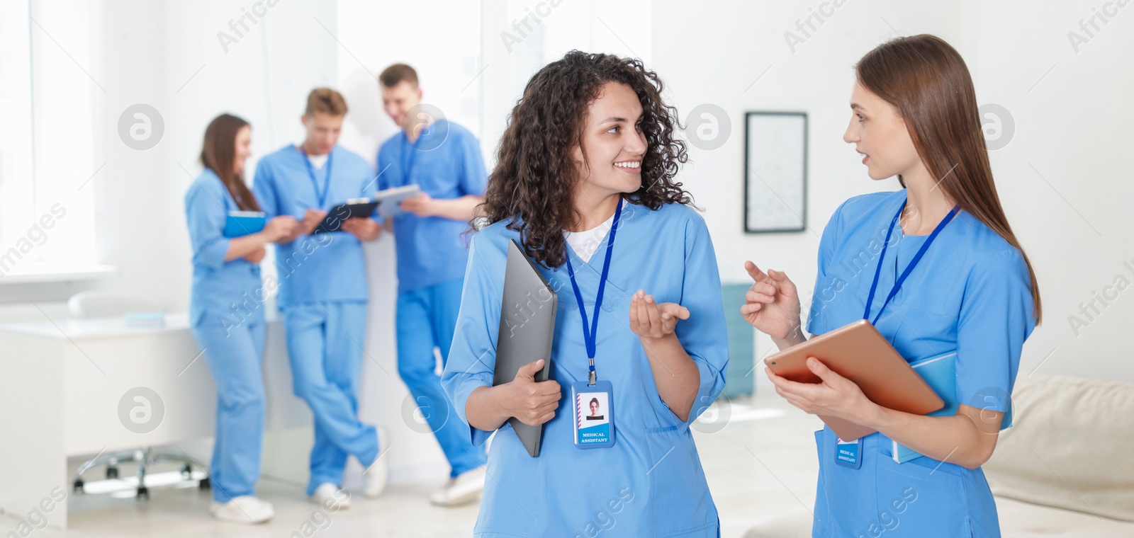 Photo of Medical students in uniforms with tablet and laptop indoors, selective focus
