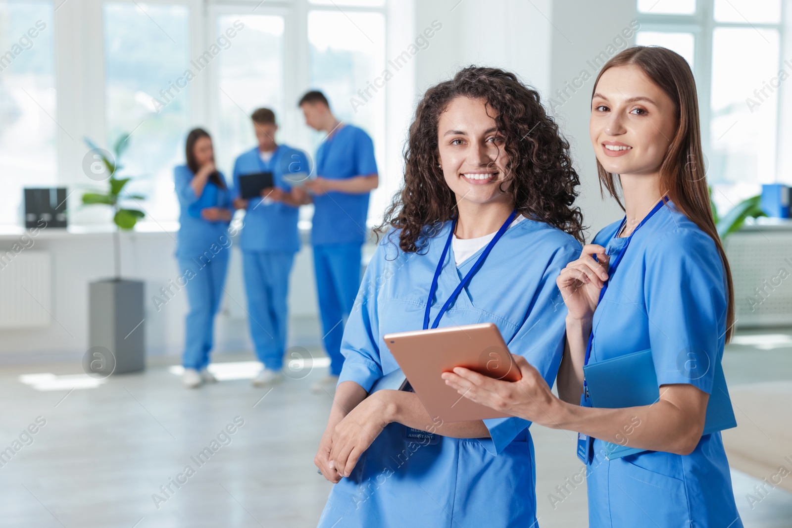Photo of Medical students in uniforms with tablet and laptop indoors, selective focus