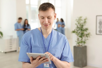 Photo of Medical student in uniform with tablet indoors, selective focus