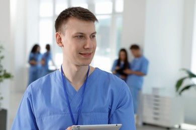 Photo of Medical student in uniform with tablet indoors, selective focus