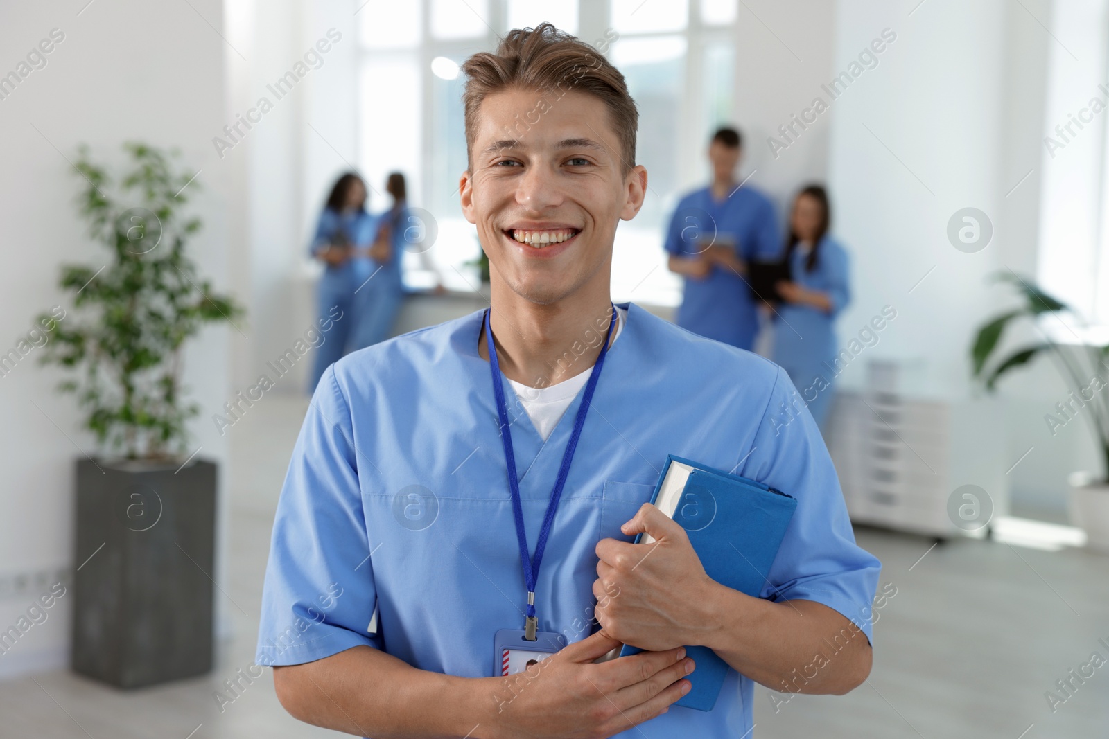 Medical student in uniform with book indoors, selective focus Photo of Medical student in uniform with book indoors, selective focus
