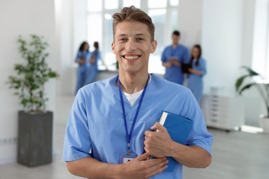 Photo of Medical student in uniform with book indoors, selective focus