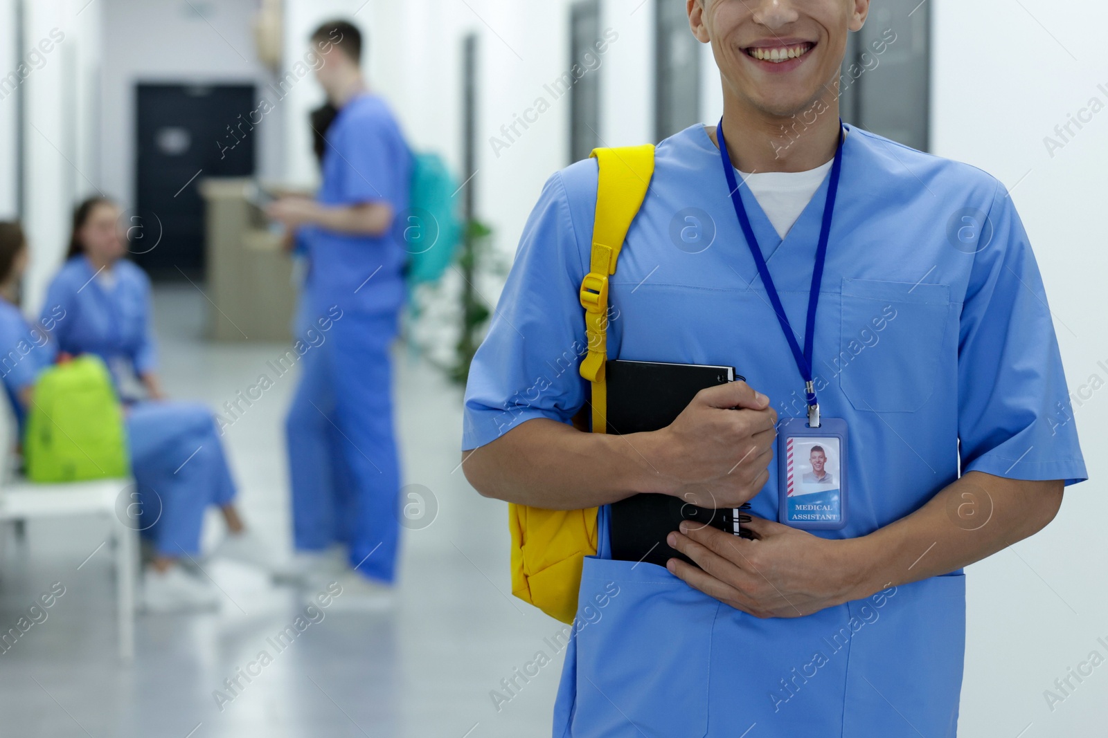 Photo of Medical student in uniform with backpack and notebook at university, selective focus